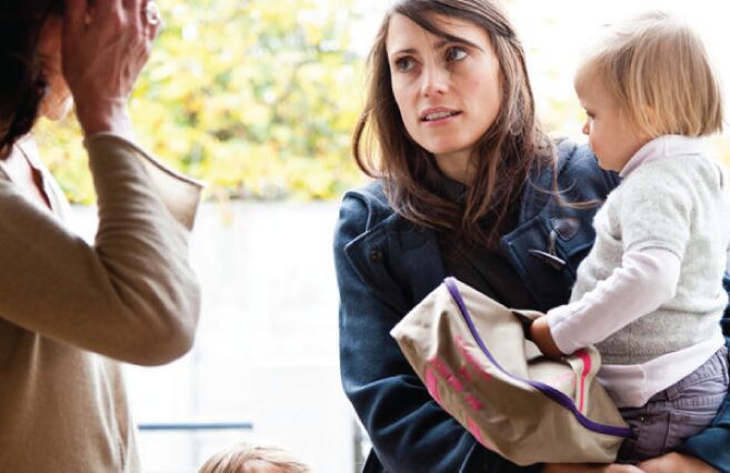 Two women conversing, one holding a child